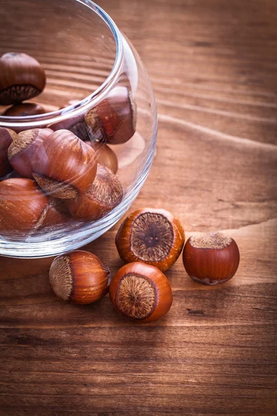 Hazelnuts and transparent round glass bowl — Stock Photo, Image