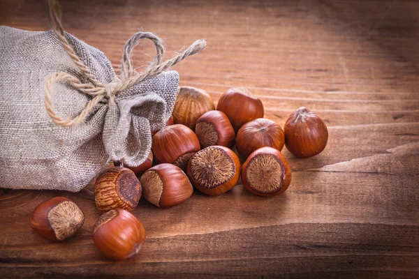 Lískové ořechy pytel na dřevěné desce — Stock fotografie