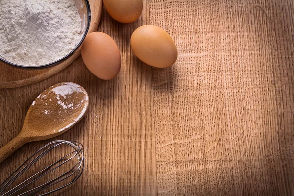 Eggs flour in bowl on wooden board — Stock Photo, Image