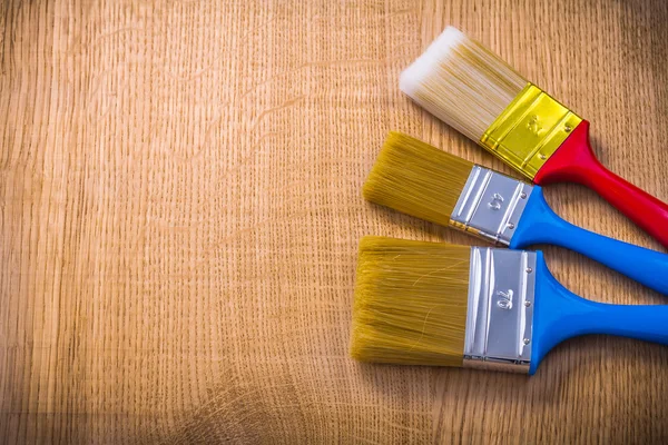 Три кисти для краски на деревянной доске — стоковое фото