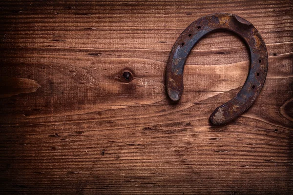 Single horseshoe on vintage wooden board — Stock Photo, Image