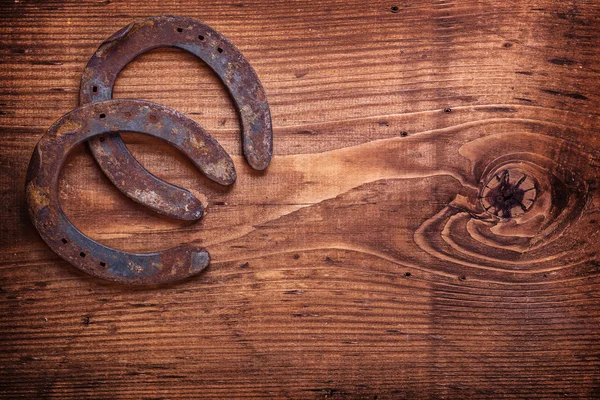 Twee hoefijzers op vintage houten bord — Stockfoto
