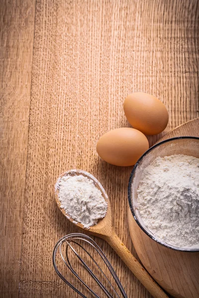 Oeufs farine dans un bol sur planche de bois — Photo