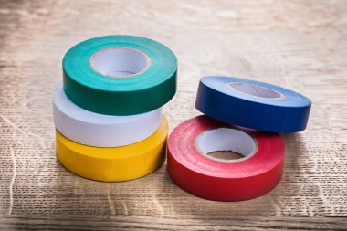 Rolls of insulating tape on wooden board clipart