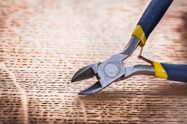 Opened nippers on wooden board — Stock Photo, Image