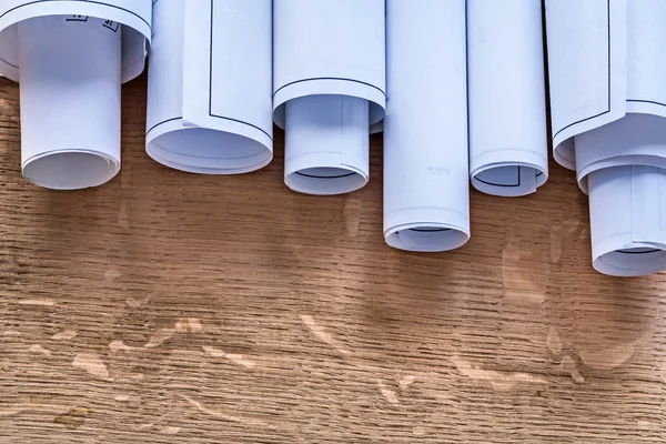 Rolls of blueprints on wooden board — Stock Photo, Image