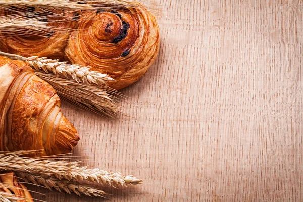 Wheat ears, croissant bun with raisins — Stock Photo, Image