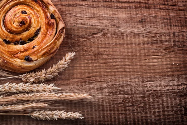 Panino di uva passa e mazzetto di spighe di grano — Foto Stock