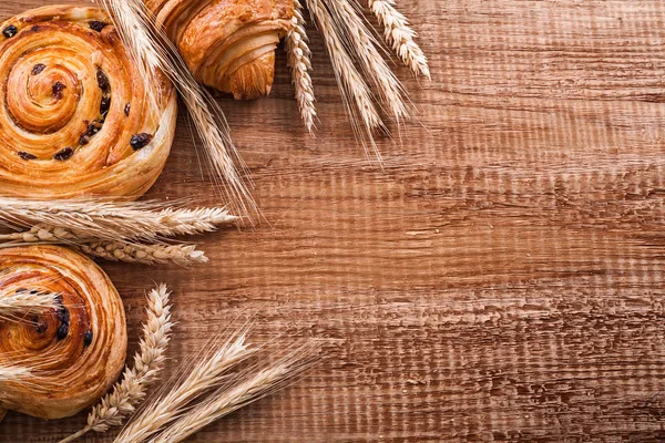 Пшеничные уши, булочки с изюмом и круассан — стоковое фото