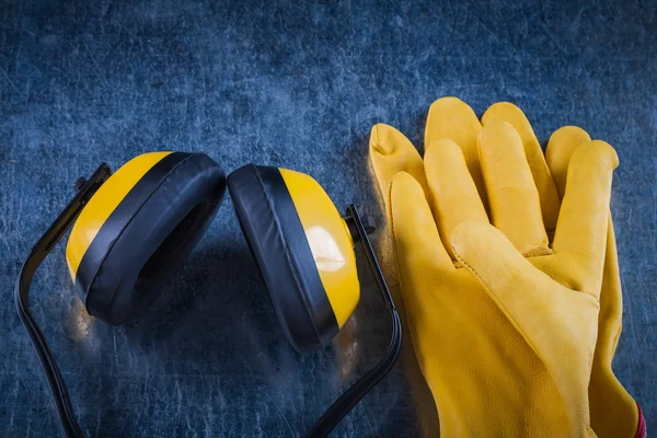 Protective yellow earmuffs and leather gloves — Stock Photo, Image