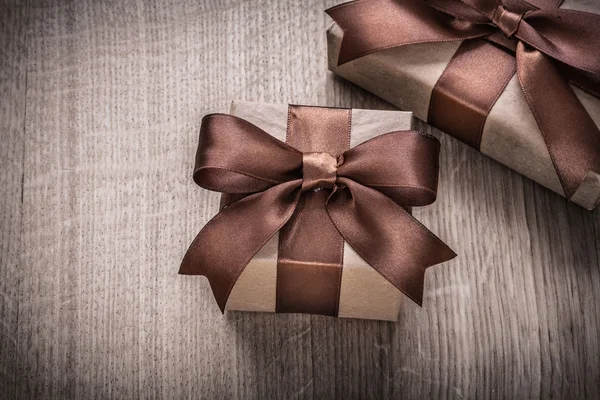 Geschenkboxen mit braunen Schleifen auf Holz — Stockfoto