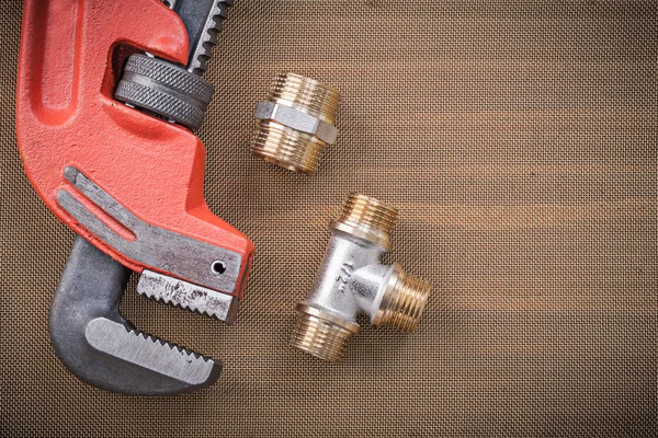 Pipe wrench and brass plumbing fixtures — Stock Photo, Image