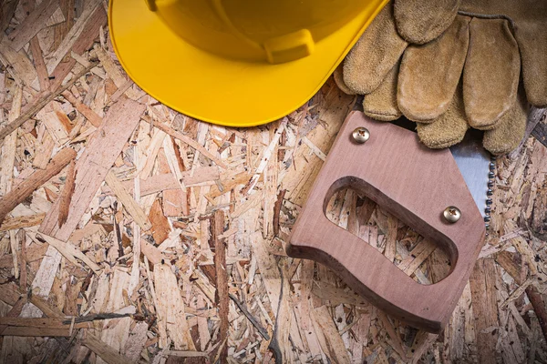 Guantes de cuero, casco de construcción, sierra manual — Foto de Stock