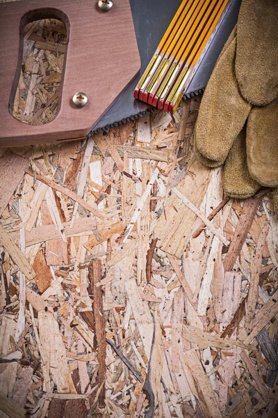 Leather gloves, wooden meter and handsaw — Stock Photo, Image