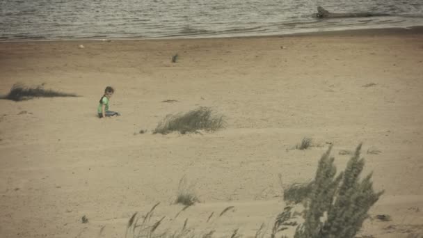 Niño triste sentado en una orilla del río — Vídeos de Stock