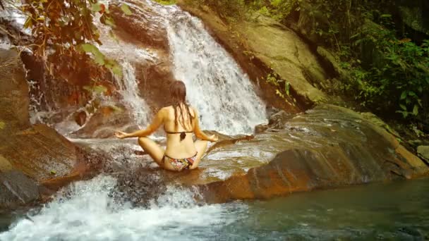 Mulher meditando perto de uma cachoeira tropical. Tailândia. Phuket. — Vídeo de Stock