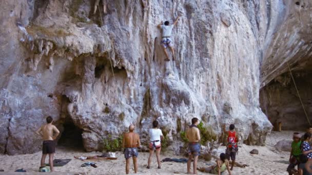 Valiente turista intentando escalar el acantilado de piedra caliza en Railay Beach. un destino turístico popular en Tailandia . — Vídeos de Stock