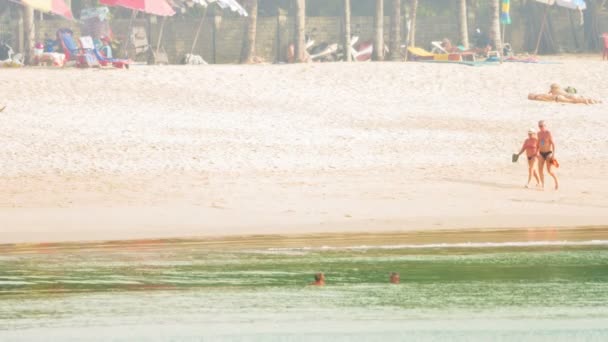 คาลาลาลาลา ฟูเค็ท ไทยแลนด์ - CIRCA DEC 2014: นักท่องเที่ยวต่างชาติเพลิดเพลินกับวันที่แดดร้อนบนชายหาดทรายสีขาว . — วีดีโอสต็อก