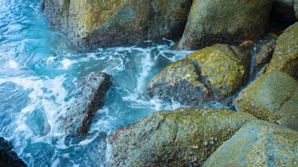 Klares Wasser schwappt auf große bemooste Felsen — Stockvideo