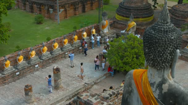 Ayutthaya. Thailand-circa feb 2015: toeristen die rij identieke boeddhabeelden bekijken in een oude tempel binnenplaats in wat Yai Chai Mongkhon in Ayutthaya. Thailand. — Stockvideo