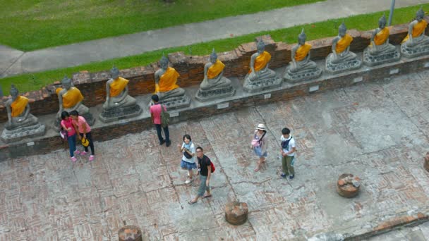 Sim, sim. THAILAND - CIRCA FEB 2015: Grupo de Turistas Olhando para uma Fileira de Esculturas Idênticas de Buda em Wat Yai Chai Mongkhon no Parque Histórico de Ayutthay, na Tailândia . — Vídeo de Stock