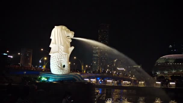 The dramatically lighted Merlion fountain. with a continuous spray of water into Marina Bay. with Singapore's nighttime skyline in the background — Stock Video