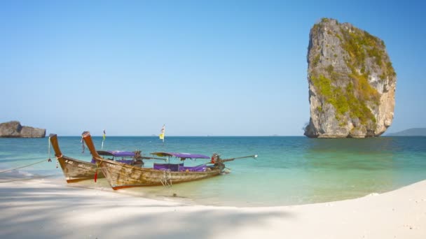 Handgemacht. hölzerne Ausflugsboote an einem beliebten Touristenstrand festgebunden. unter den Kalksteinklippen am Strand von Railay in Thailand. — Stockvideo