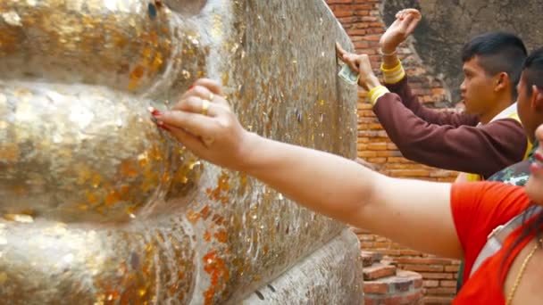 AYUTTHAYA. TAILANDIA - CIRCA FEB 2015: Adoradores Presionando moneda sobre la hoja de oro sobre la estatua de Buda como ofrenda en Wat Yai Chai Mongkhon . — Vídeo de stock