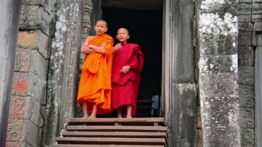 Siem Reap. Kamboçya - Circa Aralık 2013: Geleneksel cüppeiki çocuk rahipler, Siem Reap'teki Bayon Tapınağı'nın kapısında dururken kameranın bilincindedir. Kamboçya.