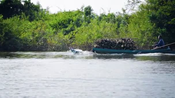 Η λίμνη Τόνλε ΜΣΣ. Καμπότζη-περίπου Δεκ 2013: ο άνθρωπος της Καμπότζης που κουβαλάει ένα φορτίο κομμένα καυσόξυλα στην αγορά με το χειροποίητο ξύλινο σκάφος του. — Αρχείο Βίντεο