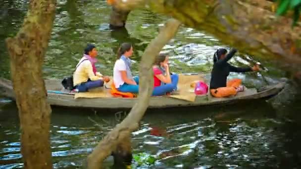 Tonle Sap Gölü. Kamboçya - Circa Aralık 2013: Turistler kamboçya nehrini gezerken iki sandal işgal ediyor. Yerel bir rehber olarak ağaçların arasından kürekçeken bir kürekçi siteleri işaret eder. — Stok video