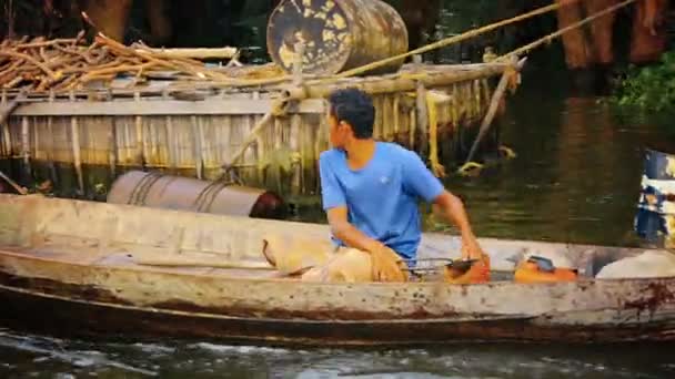 TONLE SAP LAKE. CAMBODGE - CIRCA DEC 2013 : Un batelier cambodgien descend la rivière. gouverner son canot motorisé d'une main pendant qu'il sauve l'eau avec l'autre . — Video