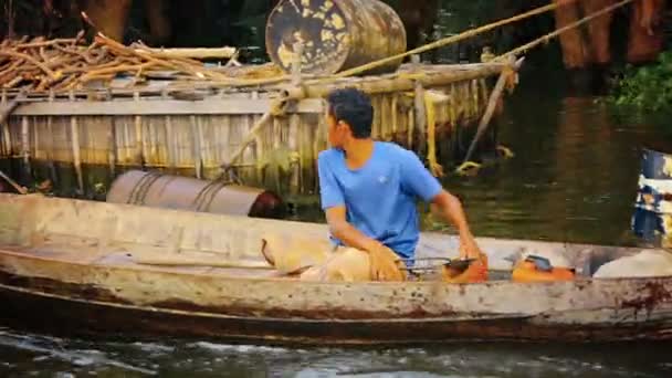 Tonle SAP Lake. Kambodzsa-Circa december 2013: kambodzsai hajós cirkál le a folyón. kormányzott a motoros kenu az egyik kezével, ahogy bails vizet a többi. — Stock videók