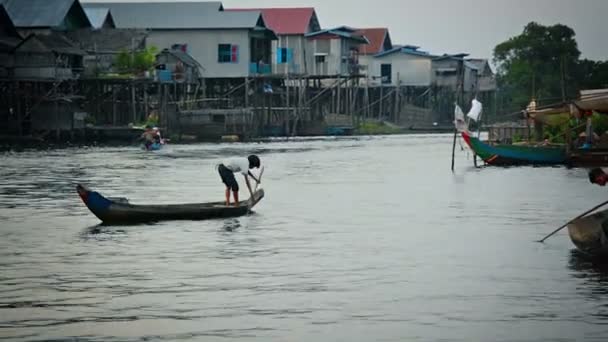 Tonle SAP Lake. Kambodža-circa dec 2013: kambodžský chlapec páduje svým ručně zhotovovaným dřevěným člunem jako motorizovaná kánoe kolem ohybu řeky — Stock video