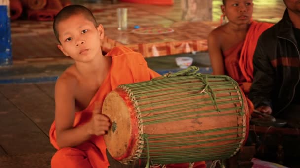 SIEM REAP. CAMBODIA - CIRCA DEC 2013: Young Cambodian monk playing a traditional music on typical. handmade. Khmer drum in Angkor Wat temple. — Stock Video