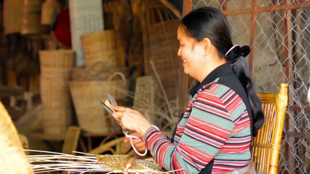 Siem Reap. CAMBODIA - CIRCA DIC 2013: Artesano local que prepara materiales y teje cestas de fibras naturales. Cestas terminadas de pie en la pantalla en el fondo. Camboya . — Vídeos de Stock