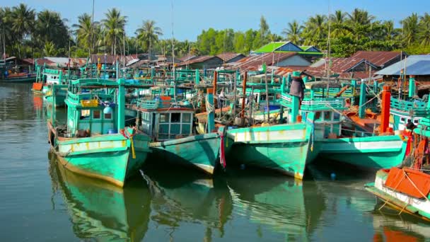 Sihanoukville. Kambodja-circa dec 2013: många handgjorda. Trä. fiskebåtar förtöjd vid småbåtshamnen i Sihanoukville. Kambodja. En pojke leker med fiskenät vid vattenbrynet. — Stockvideo