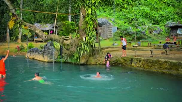 Vang Vieng. LAOS - CIRCA DIC 2013: Los turistas saltan juguetonamente a la fresca. aguas refrescantes en Blue Lagoon. un popular complejo turístico cerca de Vang Vieng. Laos . — Vídeo de stock