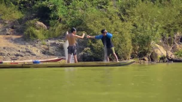 Luang prabang. laos - ca. Dez 2013: Einheimische Fischer bereiten die Netze in einem Holzkanu am Ufer eines Flusses in der Nähe von Luang Prabang vor. laos — Stockvideo