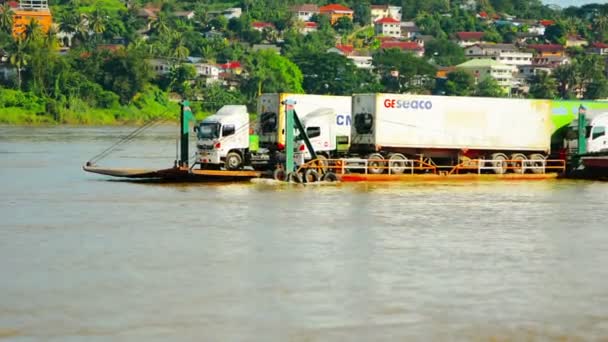 HUAY HAI. LAOS - CIRCA DIC 2013: Camiones de carga de tractores y remolques flotando río arriba en barcazas. cerca de Huay Hai. Laos . — Vídeo de stock