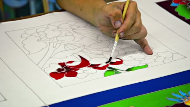 Local artist painting a red and green. floral-themed pattern by hand. — Stock Video