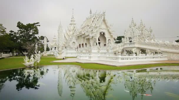 CHIANG RAI. THAÏLANDE - CIRCA DEC 2013 : Poissons dans un étang et touristes se promenant dans le temple blanc de Chiang Rai. Thaïlande. dans le temps . — Video