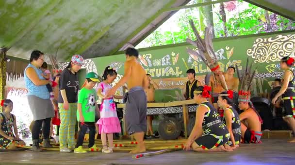 BORNEO. MALASIA - CIRCA ENE 2015: Aldeanos locales enseñan a los Magunatip danza nativa a una familia de turistas en un centro educativo cultural . — Vídeos de Stock