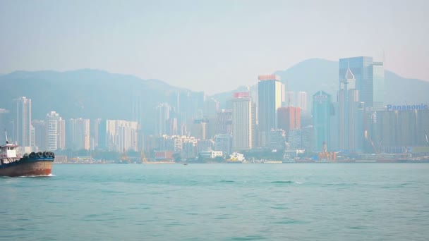 Hongkongi. Kína-Circa január 2015: A vontatóhajó. vele gumikerekes lökhárítók. hajózás előtt Hong Kong látképe. úton, hogy támogassa a kereskedelmi hajózás a Victoria Harbor. — Stock videók