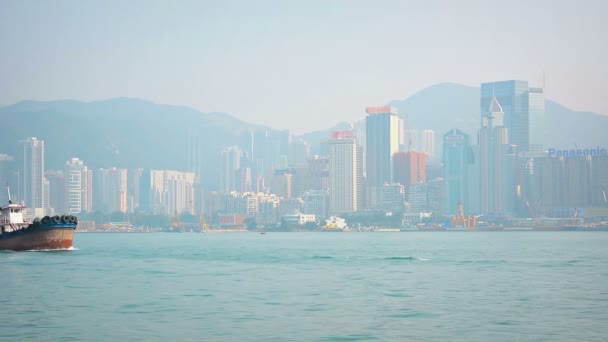 HONG KONG. CHINA - CIRCA JAN 2015: A tugboat. with it's rubber tire bumpers. cruises in front of Hong Kong's skyline. on its way to support commercial shipping in Victoria Harbor.