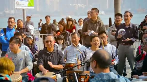 HONG KONG. CHINA - CIRCA ENE 2015: Turistas batiendo ritmos en instrumentos percusianos en la terminal mientras los pasajeros esperan el próximo ferry en el fondo . — Vídeos de Stock