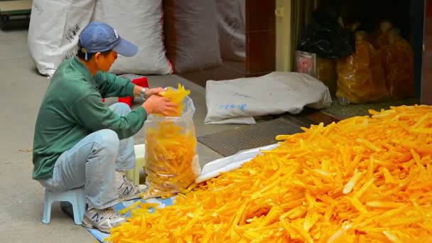 Hongkong. China-circa Jan 2015: lokale winkel keeper vult transparante plastic zakken met de hand. met gedroogde inktvis van een enorme stapel op de grond. — Stockvideo