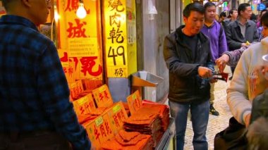 Satıcı, Macao'daki bu kalabalık ticaret bölgesinde yoldan geçenler için bir ürünün örneklerini kesiyor. Çin.