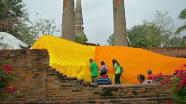 Büyük bir Buda heykelini dev bir heykelle kaplayan işçiler. Turuncu. Tayland 'daki Ayutthaya Tarihi Parkı' nda kumaş yaprağı.