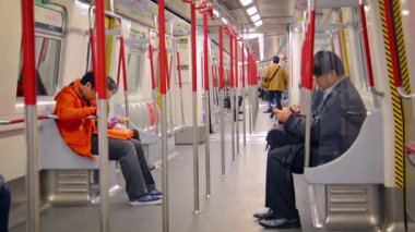 Hong Kong şehir merkezinde bir metro treninde gidip gelen yolcular akıllı telefonlarını kullanıyorlar. ses ile.